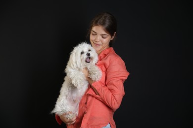 Photo of Happy teenage girl with Maltese dog on black background