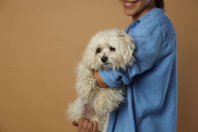 Photo of Happy teenage girl with Maltese dog on beige background, closeup. Space for text