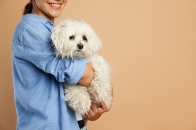 Photo of Happy teenage girl with Maltese dog on beige background, closeup. Space for text