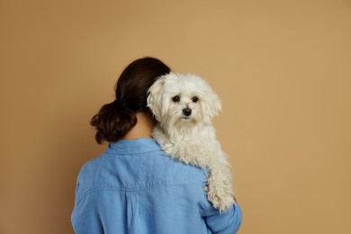 Photo of Happy teenage girl with Maltese dog on beige background, back view