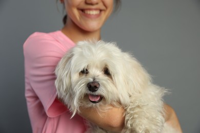 Photo of Happy teenage girl with Maltese dog on grey background, closeup