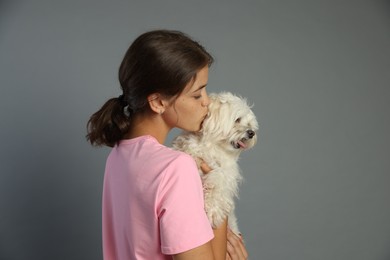 Photo of Happy teenage girl with Maltese dog on grey background