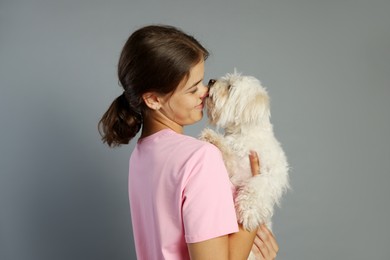 Photo of Happy teenage girl with Maltese dog on grey background