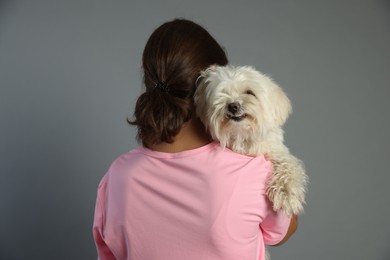 Photo of Happy teenage girl with Maltese dog on grey background, back view