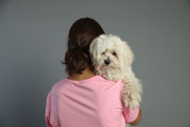 Photo of Happy teenage girl with Maltese dog on grey background, back view