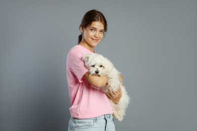 Photo of Happy teenage girl with Maltese dog on grey background