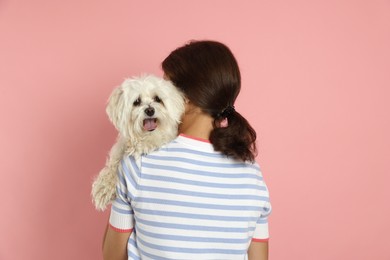 Photo of Happy teenage girl with Maltese dog on pink background, back view