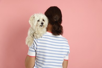 Photo of Happy teenage girl with Maltese dog on pink background, back view