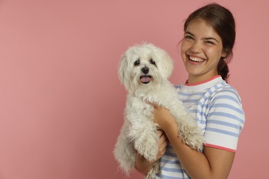 Photo of Happy teenage girl with Maltese dog on pink background, space for text