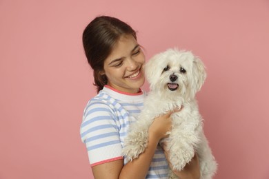 Photo of Happy teenage girl with Maltese dog on pink background