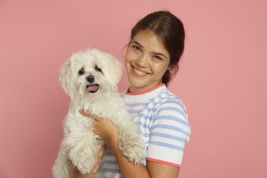 Photo of Happy teenage girl with Maltese dog on pink background