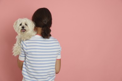 Photo of Happy teenage girl with Maltese dog on pink background, back view. Space for text