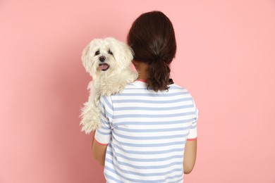Photo of Happy teenage girl with Maltese dog on pink background, back view