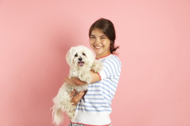 Photo of Happy teenage girl with Maltese dog on pink background