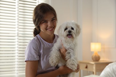 Photo of Happy teenage girl with cute Maltese dog at home