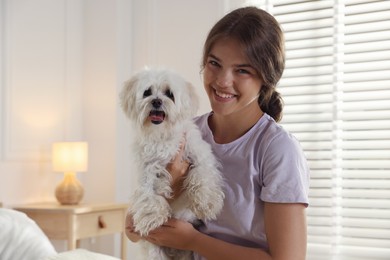 Photo of Happy teenage girl with cute Maltese dog at home