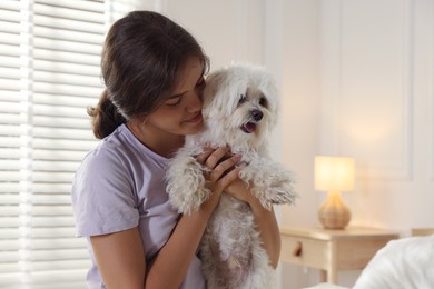 Photo of Happy teenage girl with cute Maltese dog at home