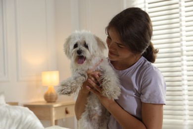 Photo of Happy teenage girl with cute Maltese dog at home
