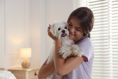 Photo of Happy teenage girl with cute Maltese dog at home