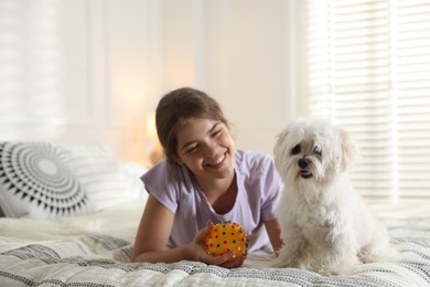 Photo of Happy teenage girl with cute Maltese dog on bed at home