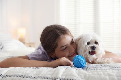 Photo of Happy teenage girl with cute Maltese dog on bed at home