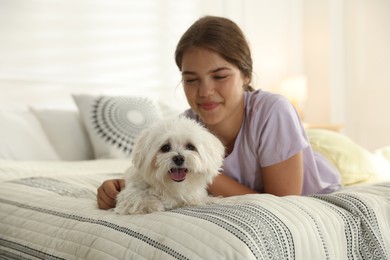 Photo of Happy teenage girl with cute Maltese dog on bed at home