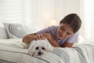 Photo of Happy teenage girl with cute Maltese dog on bed at home