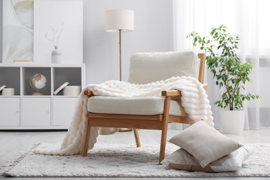 Photo of Comfortable armchair with blanket in living room. Interior design