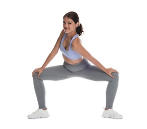 Photo of Teenage girl in sportswear stretching on white background