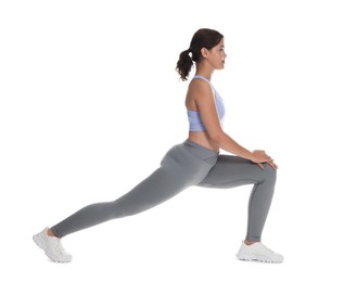 Photo of Teenage girl in sportswear stretching on white background