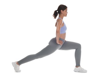 Photo of Teenage girl in sportswear stretching on white background
