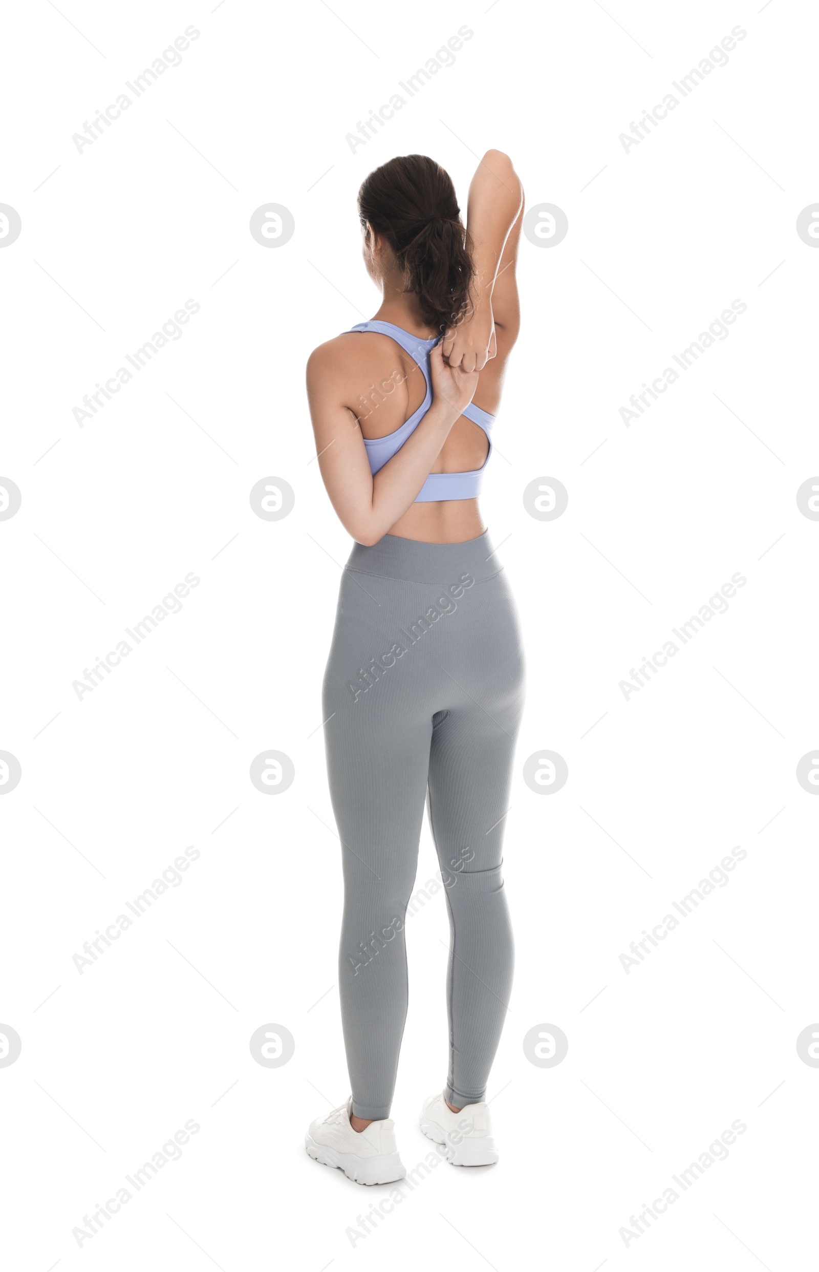 Photo of Teenage girl in sportswear stretching on white background, back view