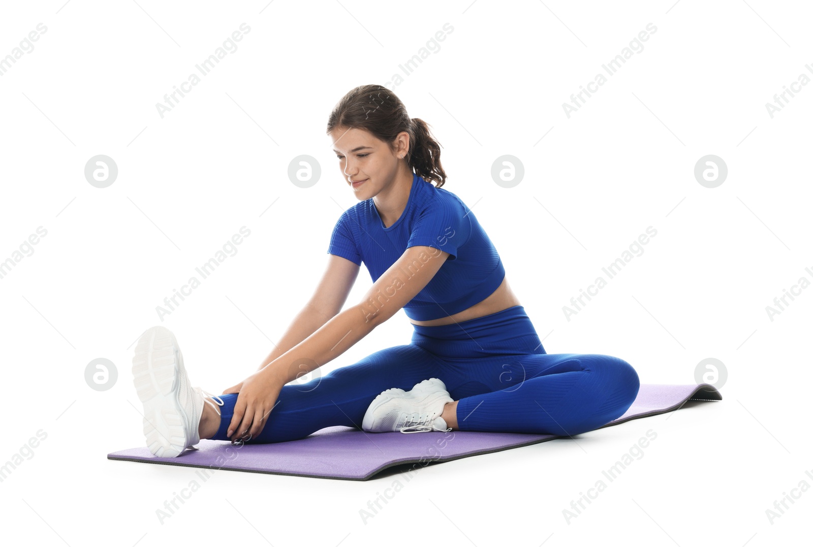 Photo of Teenage girl in sportswear stretching on mat against white background