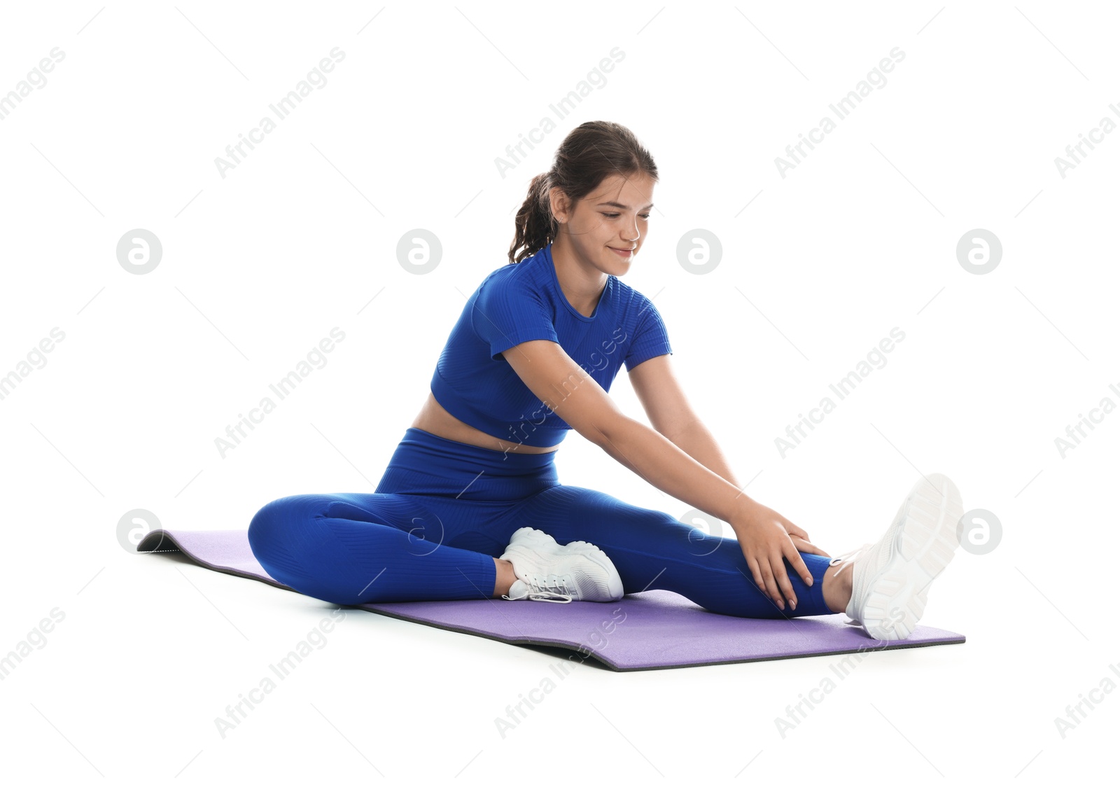 Photo of Teenage girl in sportswear stretching on mat against white background