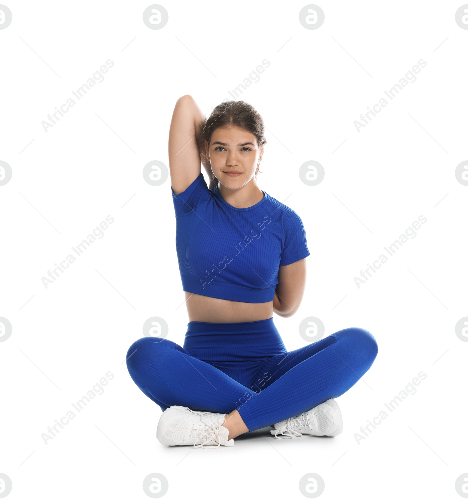 Photo of Teenage girl in sportswear stretching on white background