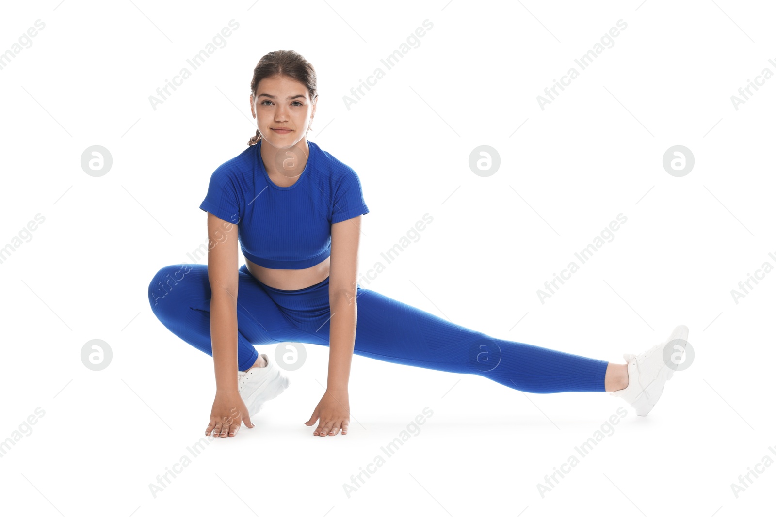 Photo of Teenage girl in sportswear stretching on white background