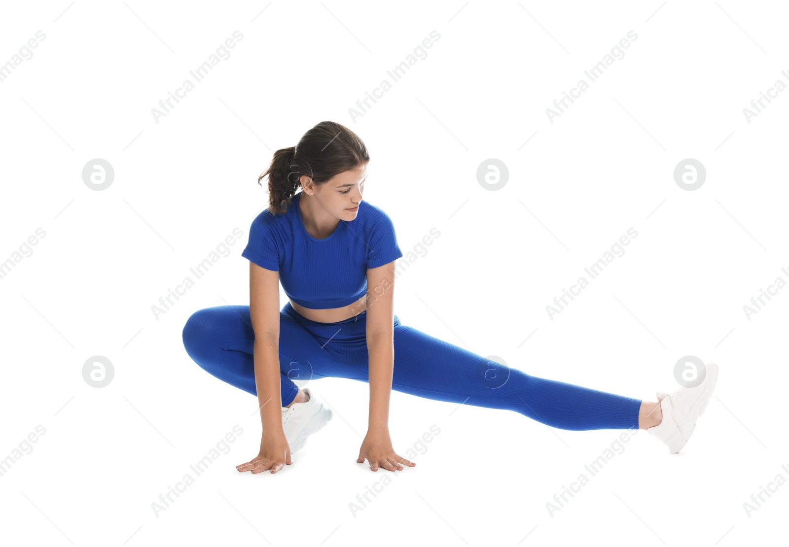 Photo of Teenage girl in sportswear stretching on white background