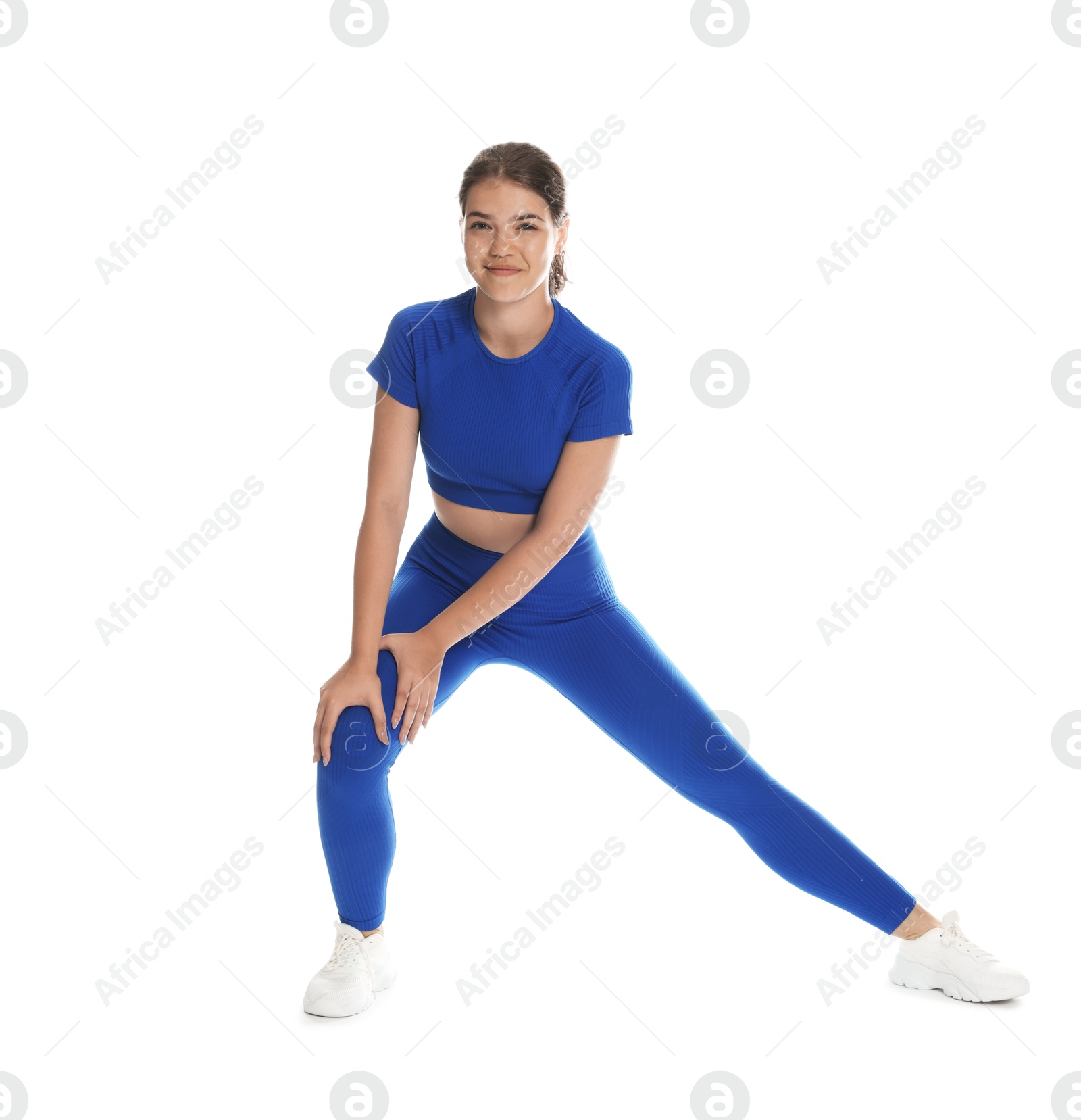 Photo of Teenage girl in sportswear stretching on white background