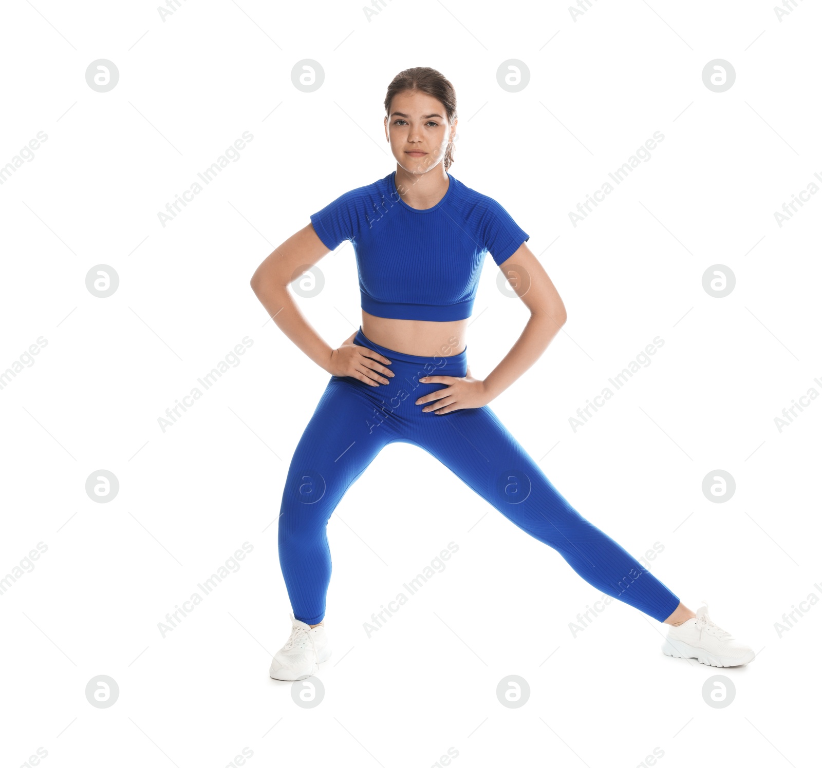 Photo of Teenage girl in sportswear stretching on white background