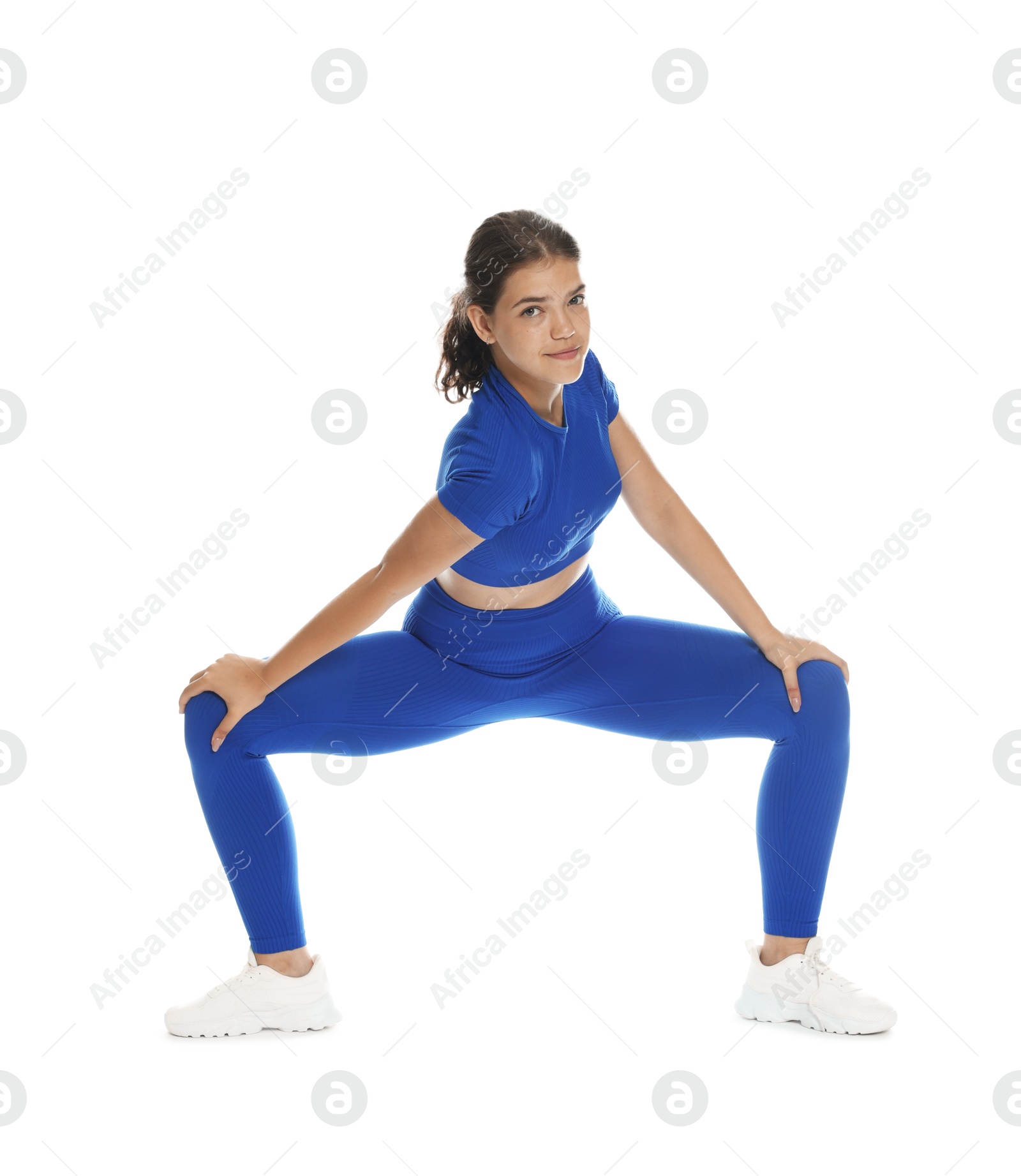 Photo of Teenage girl in sportswear stretching on white background