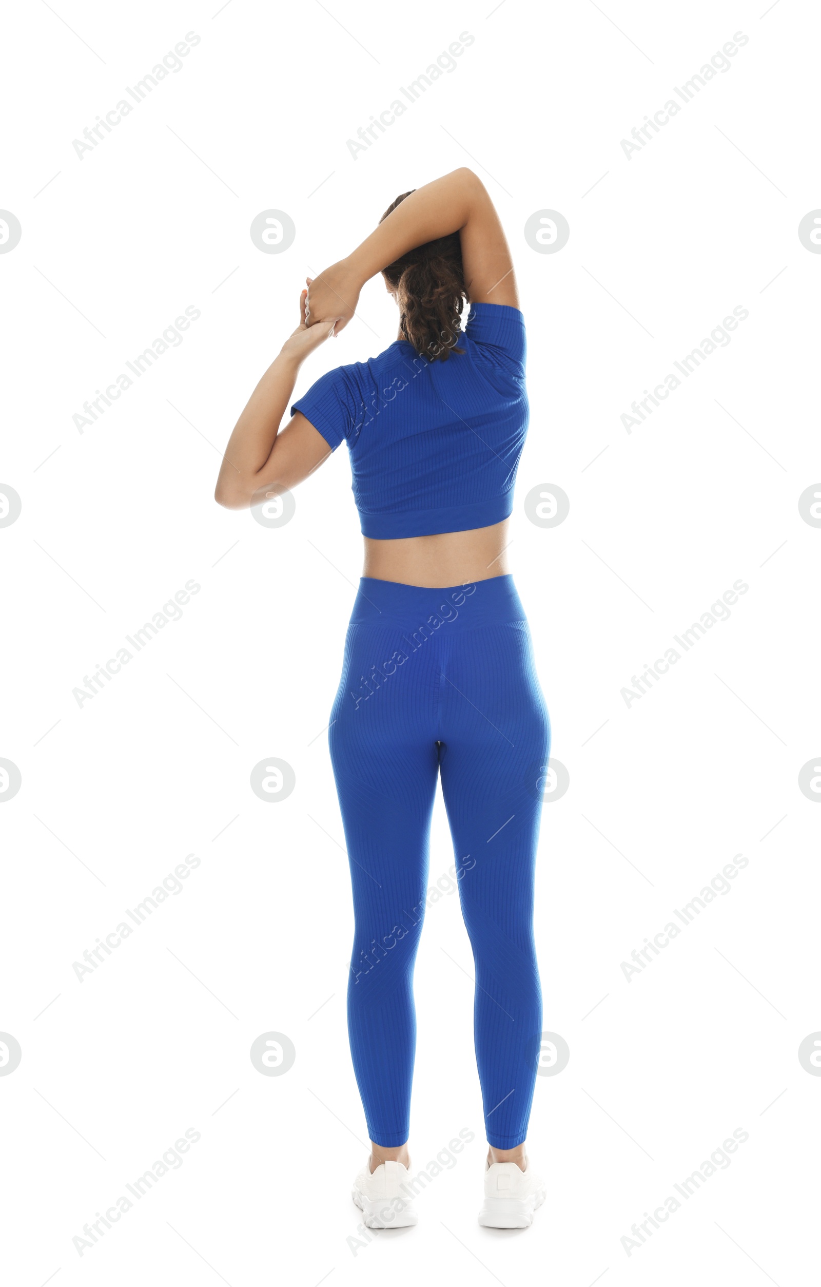 Photo of Teenage girl in sportswear stretching on white background, back view