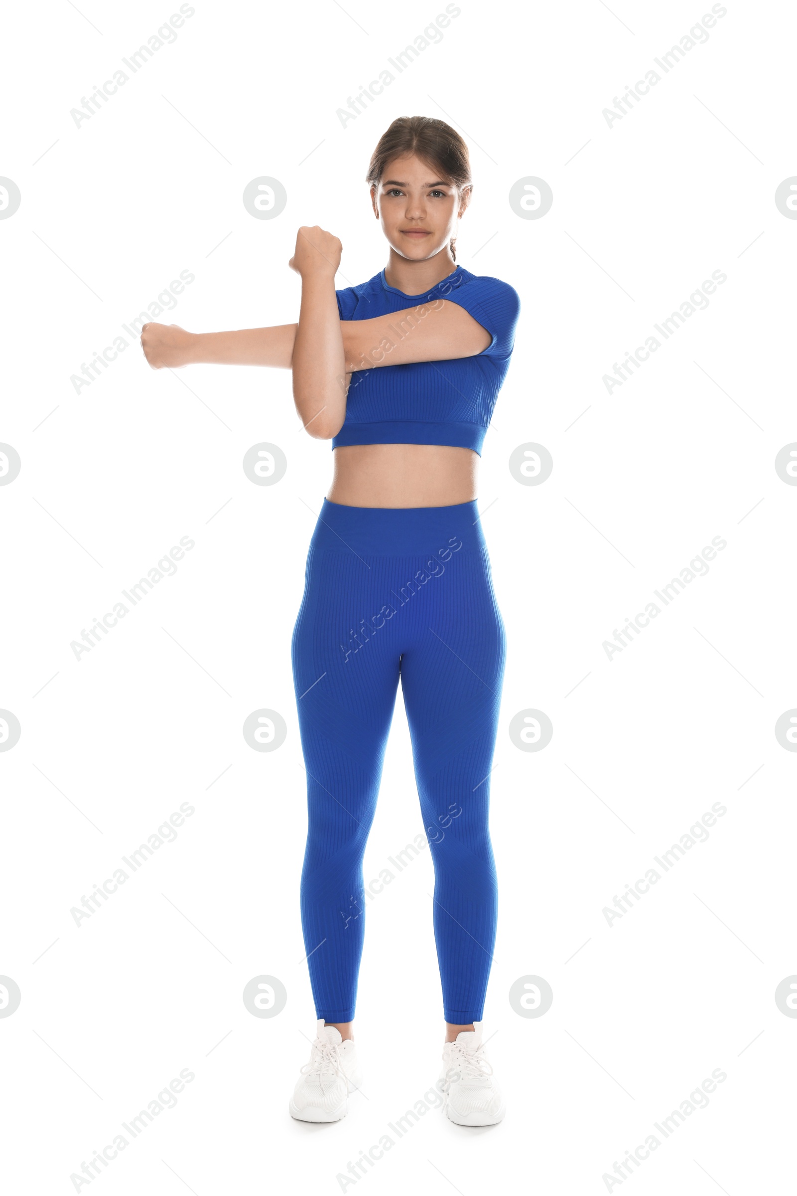 Photo of Teenage girl in sportswear stretching on white background