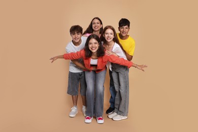 Photo of Full-length portrait of happy teenage friends on beige background