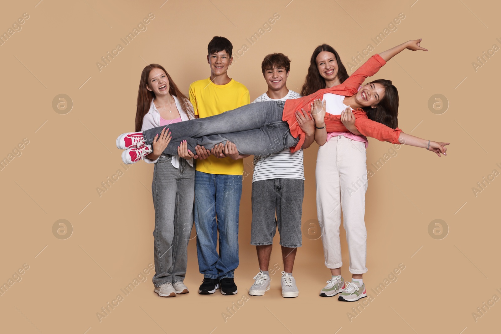 Photo of Full-length portrait of happy teenage friends on beige background