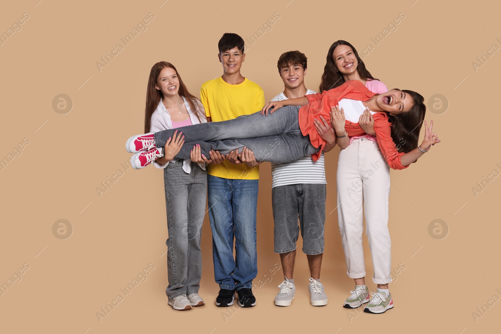 Photo of Full-length portrait of happy teenage friends on beige background