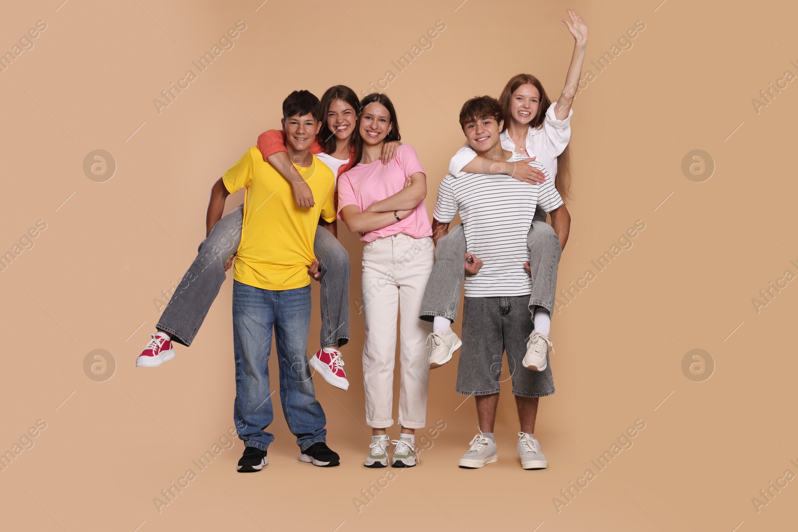 Photo of Full-length portrait of happy teenage friends on beige background