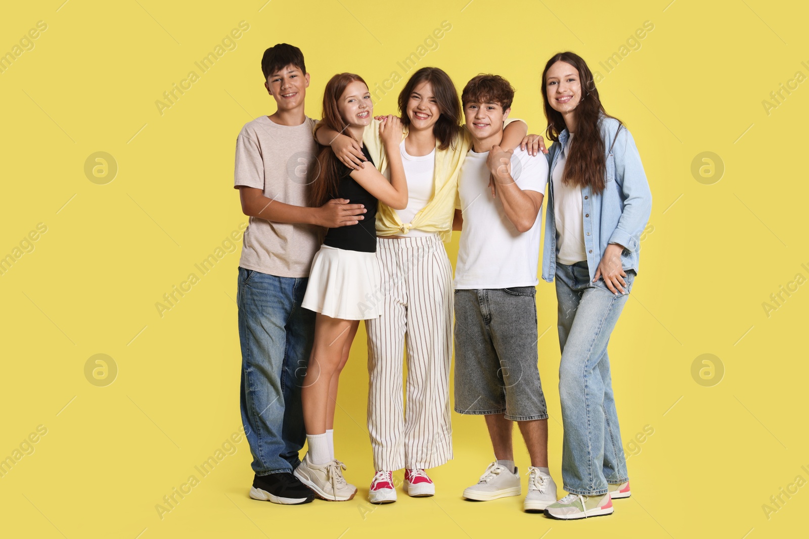 Photo of Full-length portrait of happy teenage friends on yellow background