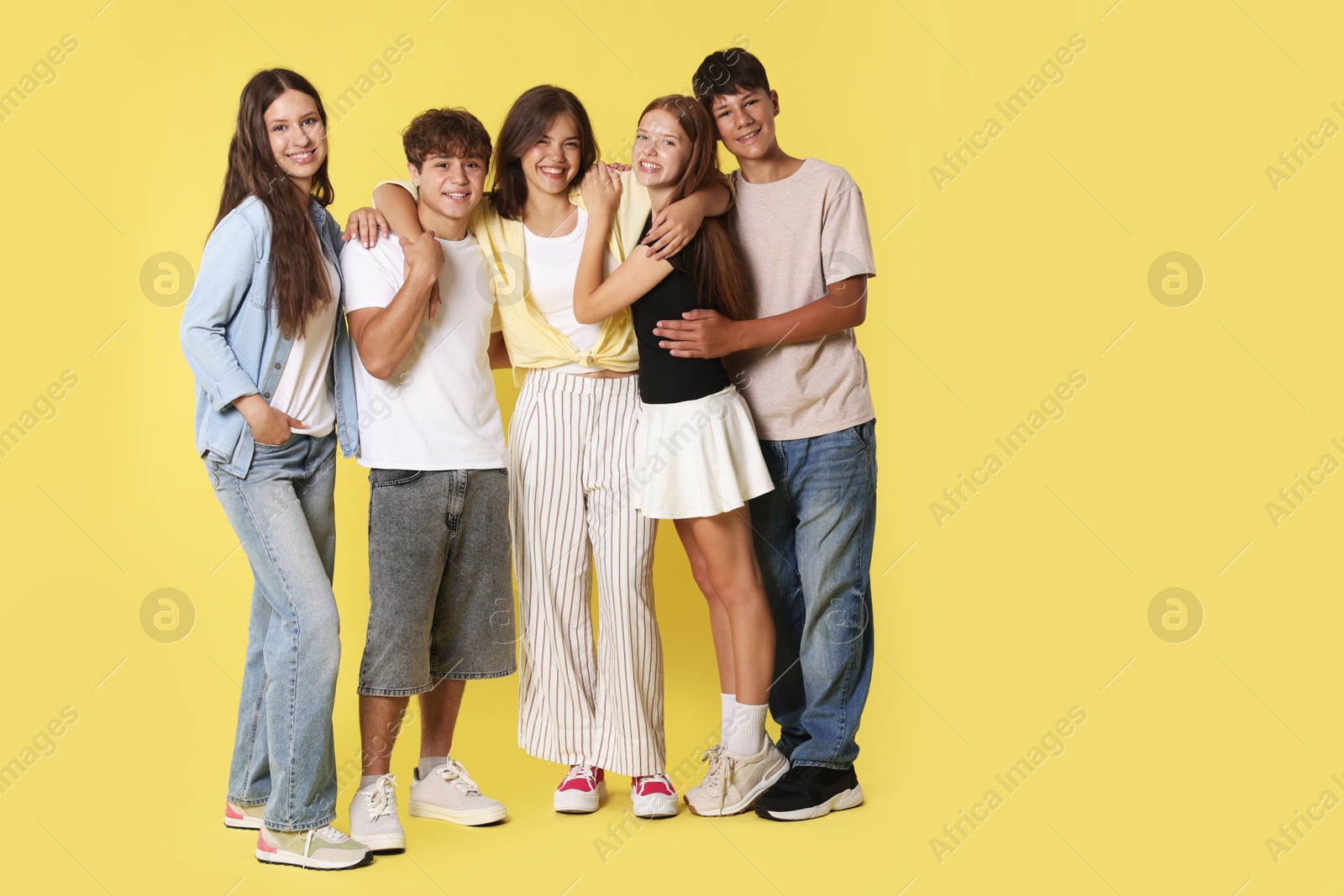 Photo of Full-length portrait of happy teenage friends on yellow background