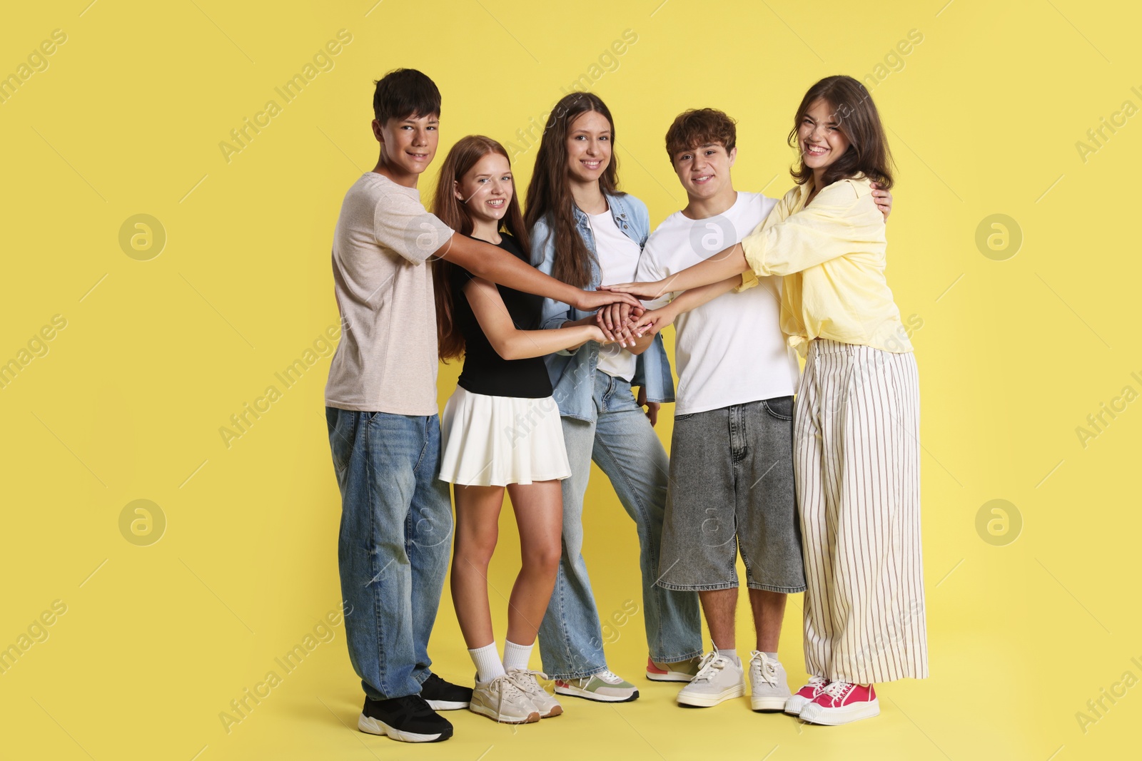 Photo of Full-length portrait of happy teenage friends on yellow background