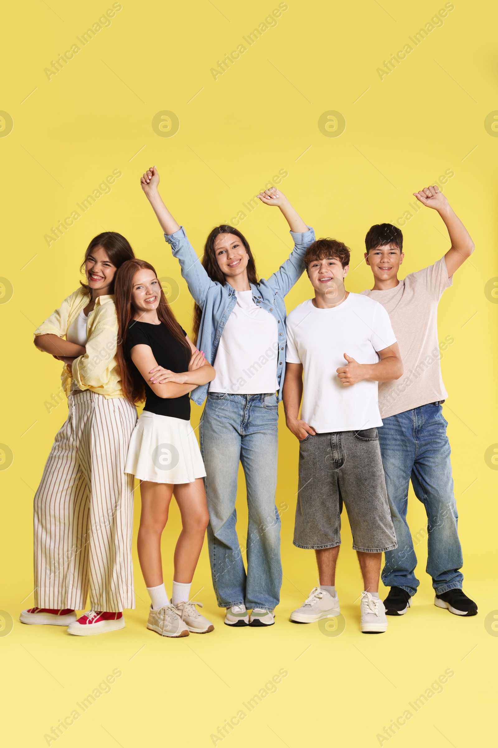 Photo of Full-length portrait of happy teenage friends on yellow background